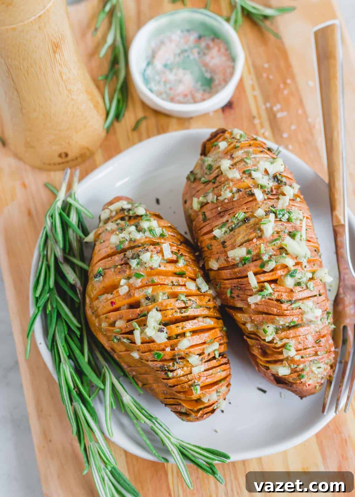 Roasted hasselback sweet potatoes with rosemary on a plate with fresh rosemary sprigs. Roasted hasselback sweet potatoes with rosemary on a plate with fresh rosemary sprigs.