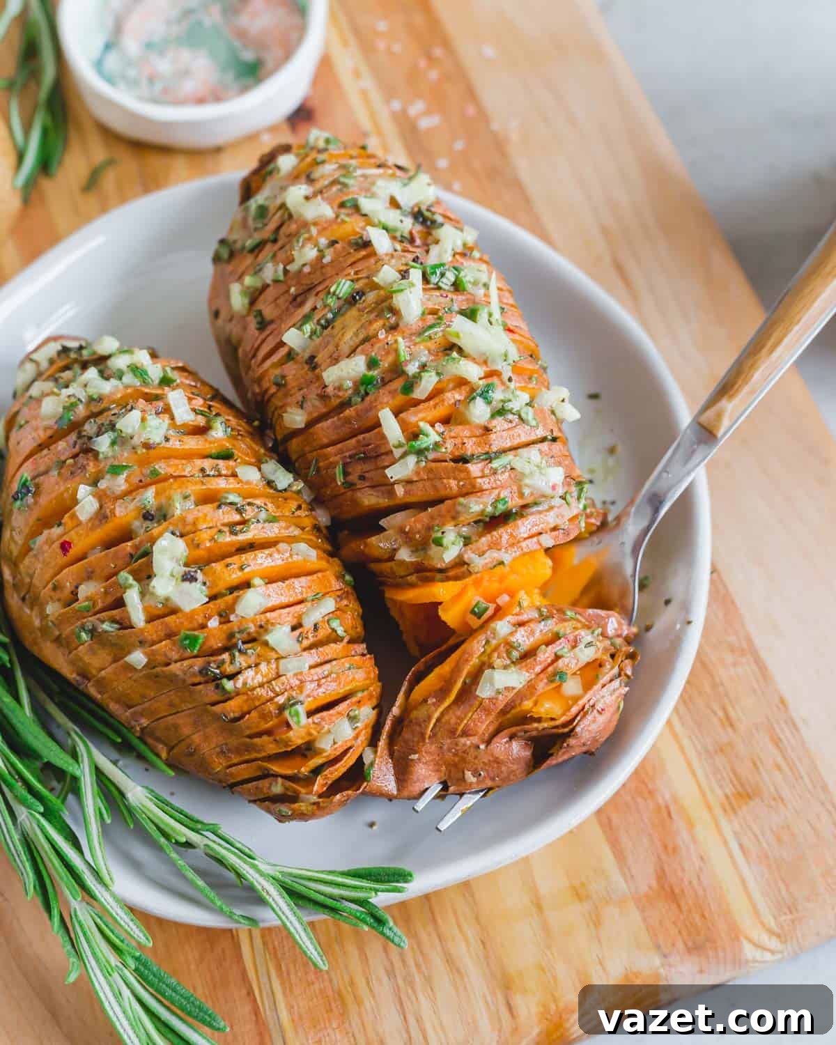Vegan hasselback sweet potatoes with rosemary mustard shallot dressing on a plate with a fork. Vegan hasselback sweet potatoes with rosemary mustard shallot dressing on a plate with a fork.