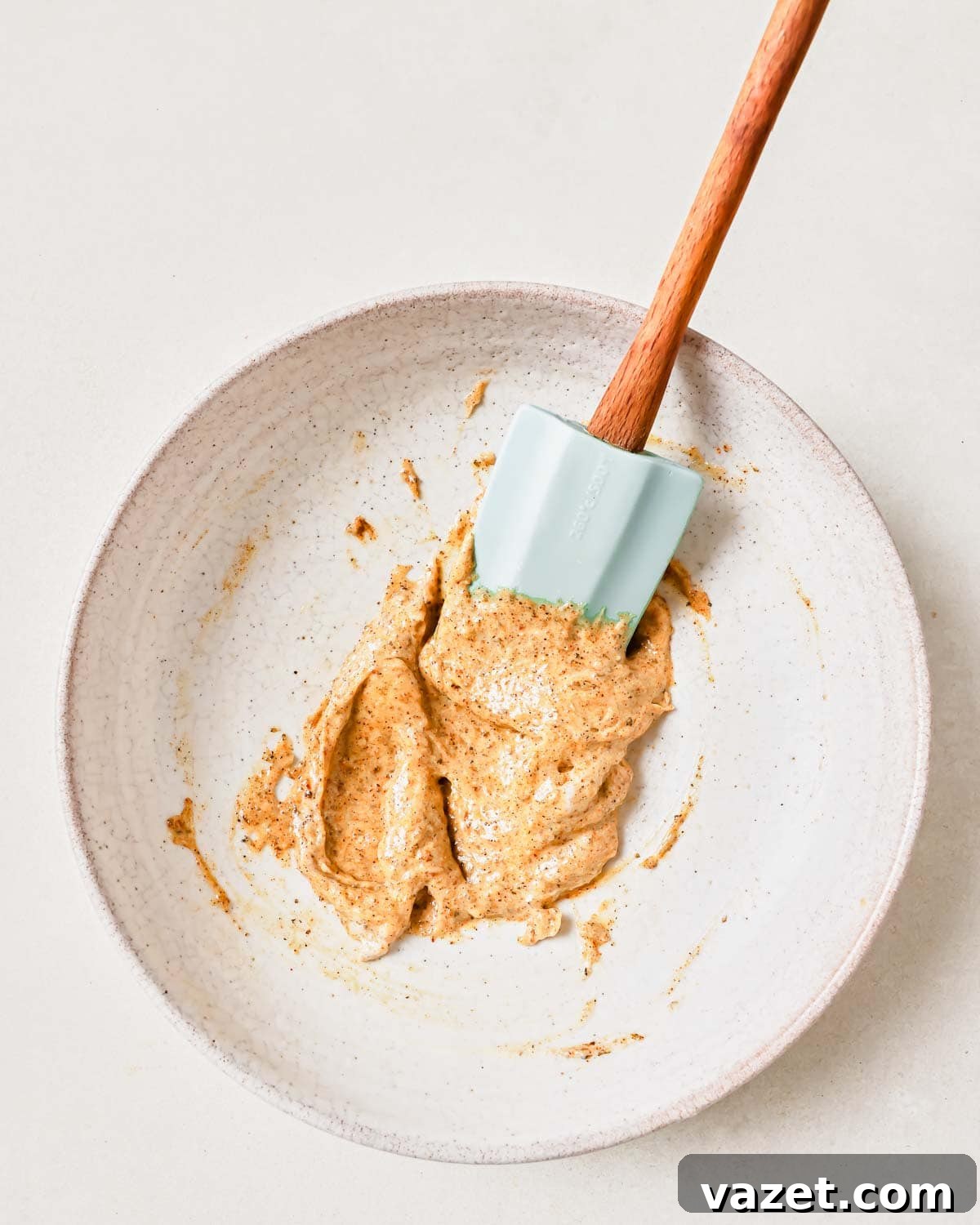 Quick Baked Shrimp Poppers 4 A bowl of creamy mayonnaise mixed with seasoning spices, ready for coating the shrimp, with a wooden spoon resting in it.