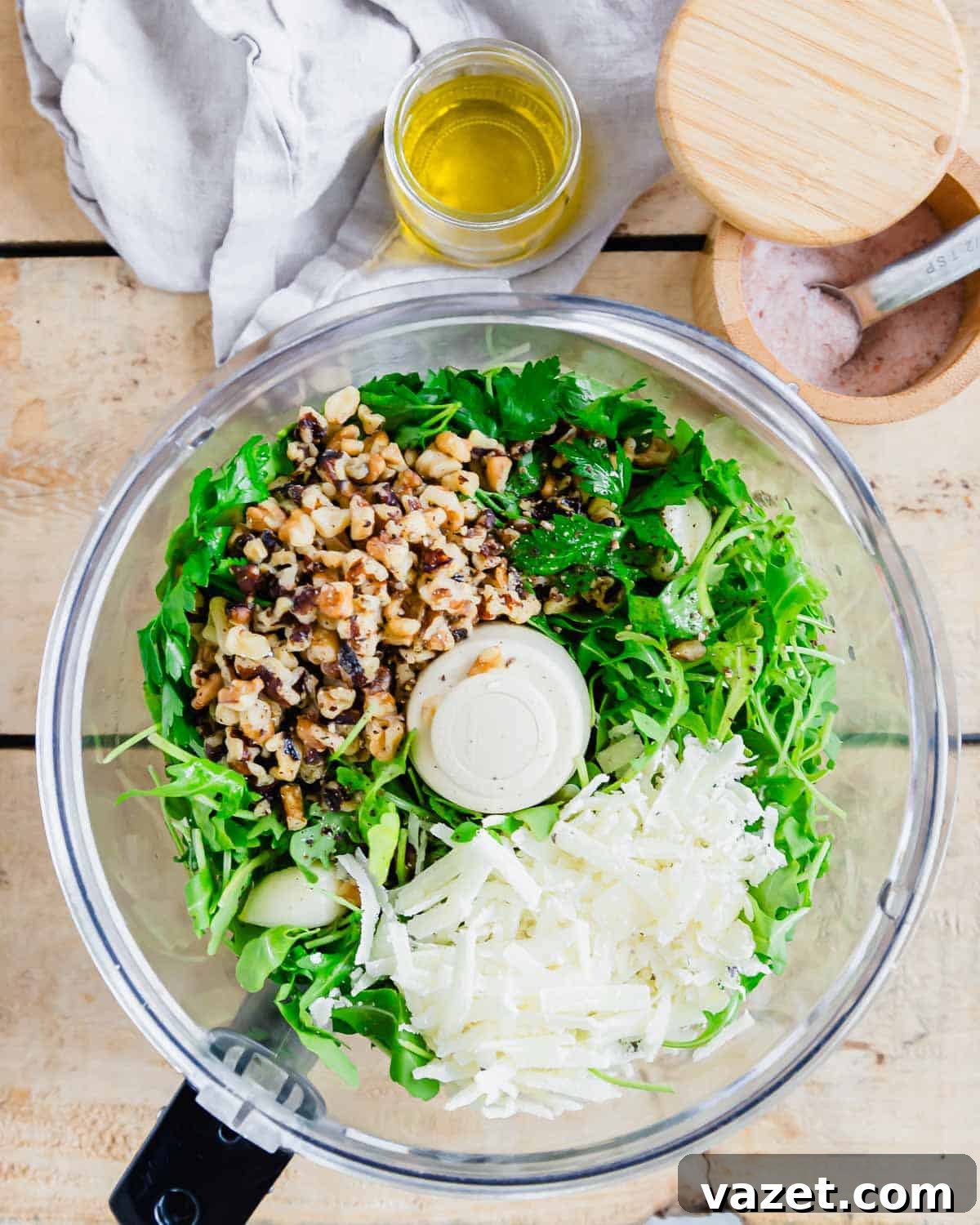 A food processor filled with ingredients for making pesto.