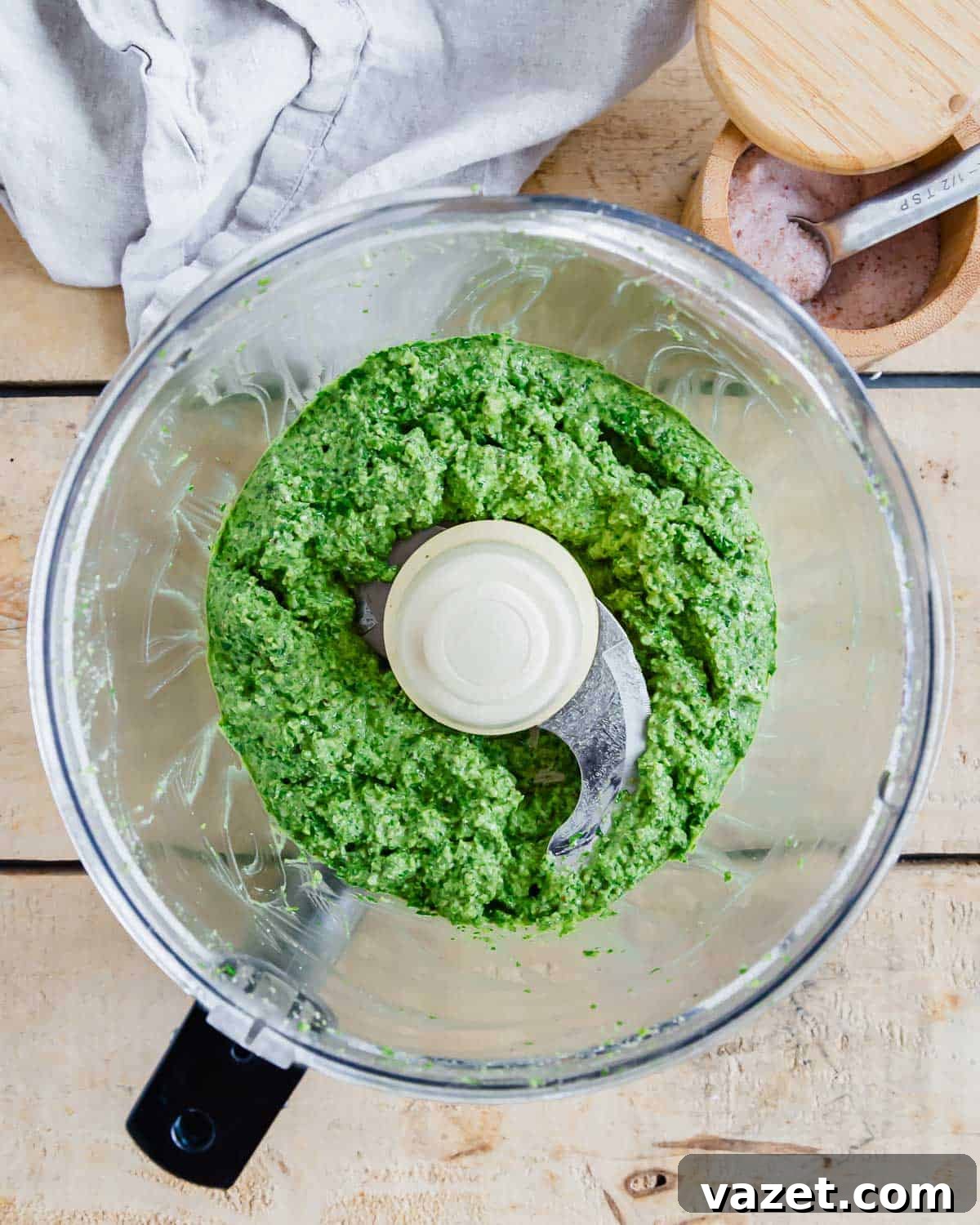 Green arugula pesto in a food processor bowl.