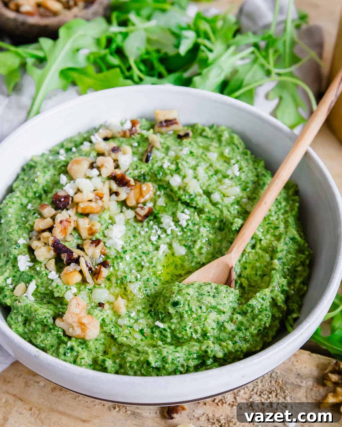 A small wooden spoon in a bowl of pesto.