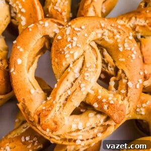 A close-up of several freshly baked soft GF pretzels sprinkled with coarse salt.