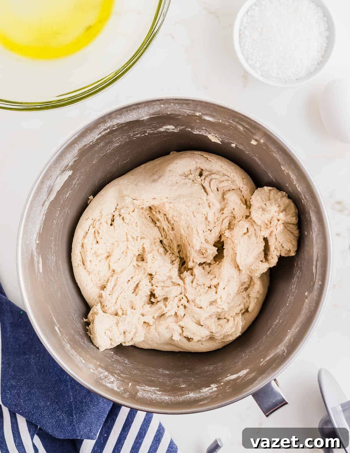 Cloud-Soft Gluten-Free Pretzels 5 A mixing bowl containing a ball of pretzel dough. Nearby are a bowl of oil, a bowl of coarse salt, an egg, and a blue and white striped cloth.