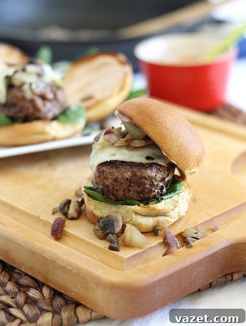 Swiss mushroom beef sliders, topped with greens, on a wooden board