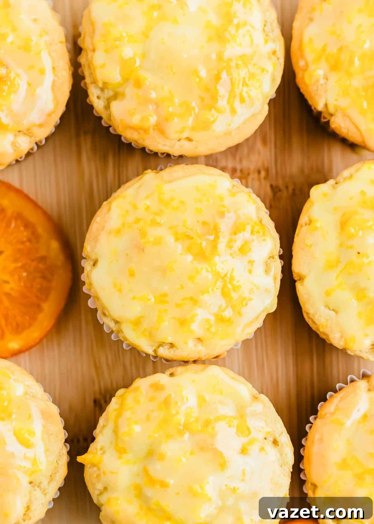 Zesty Orange Muffins 2 A wooden cutting board with orange glazed muffins on it, ready to be enjoyed.