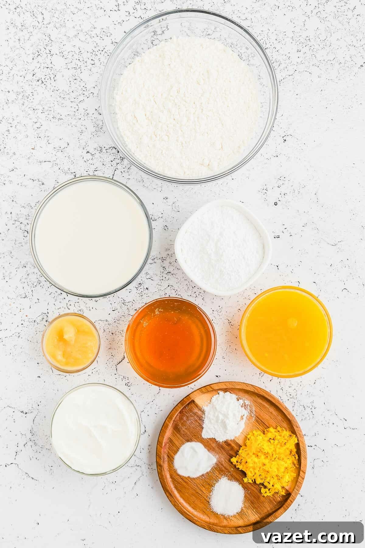 Zesty Orange Muffins 3 Various fresh ingredients for making homemade orange muffins arranged artfully on a white background.