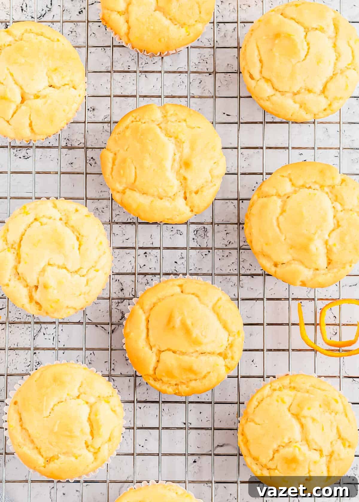 Zesty Orange Muffins 7 Orange muffins on a cooling rack, some adorned with delicate candied orange zest for garnish.
