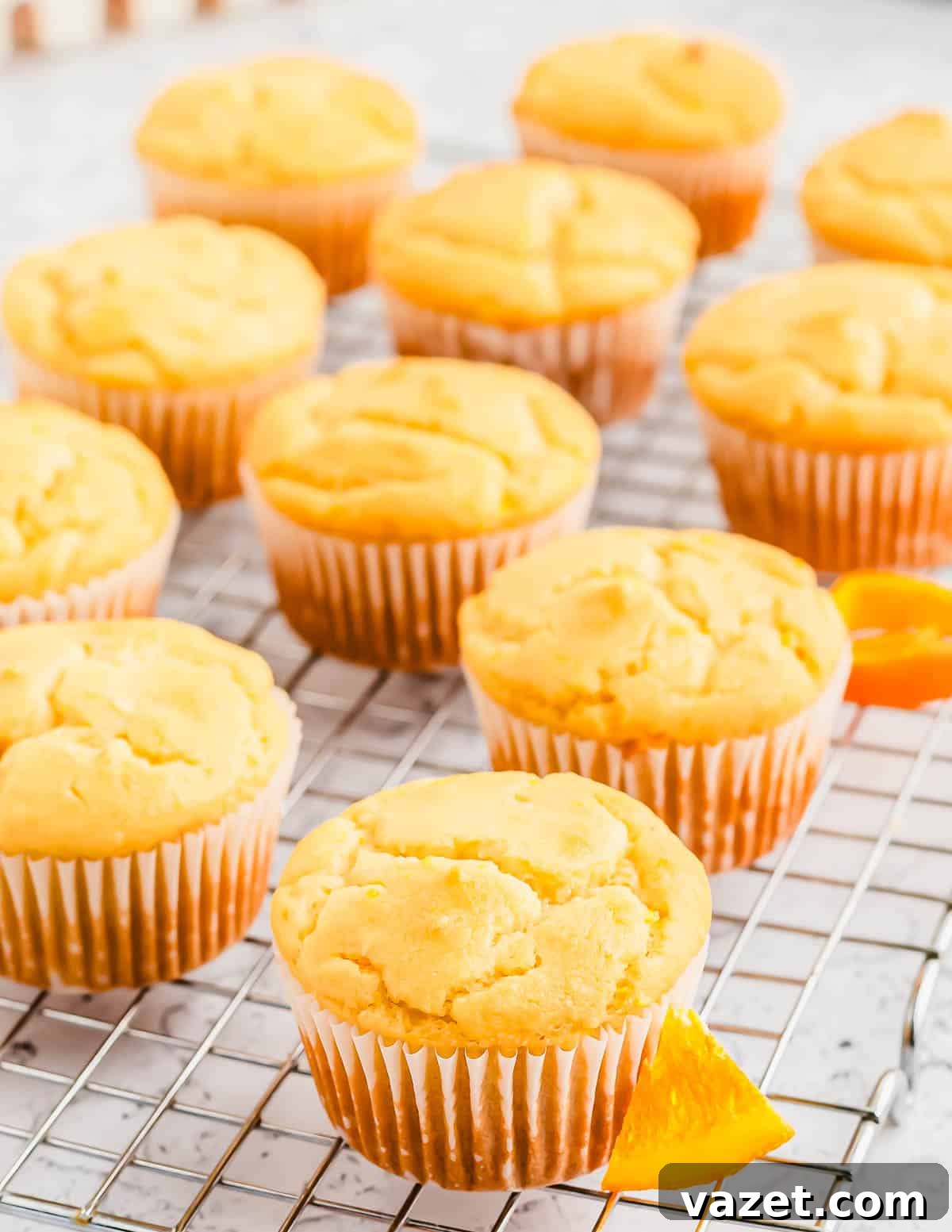 Zesty Orange Muffins 9 Perfectly baked orange muffins in parchment paper wrappers cooling gracefully on a wire rack.