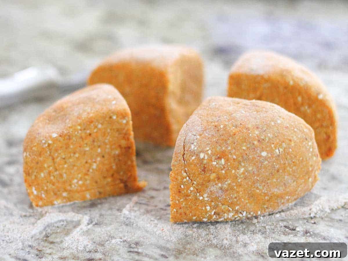 Four pieces of sweet potato gnocchi dough sit on a flour-dusted surface.