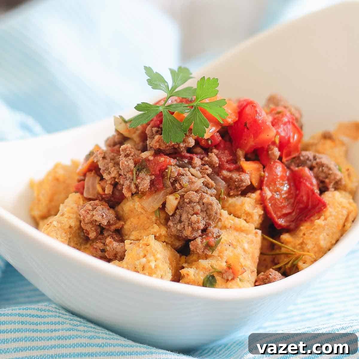 White bowl filled with a dish featuring bolognese meat sauce and sweet potato gnocchi.