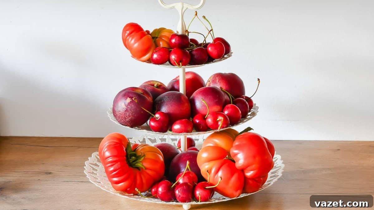 Home Freezing Tomatoes Made Simple 6 A three-tiered serving tray holds various red fruits, including apples, cherries, and peppers, placed on a wooden surface.