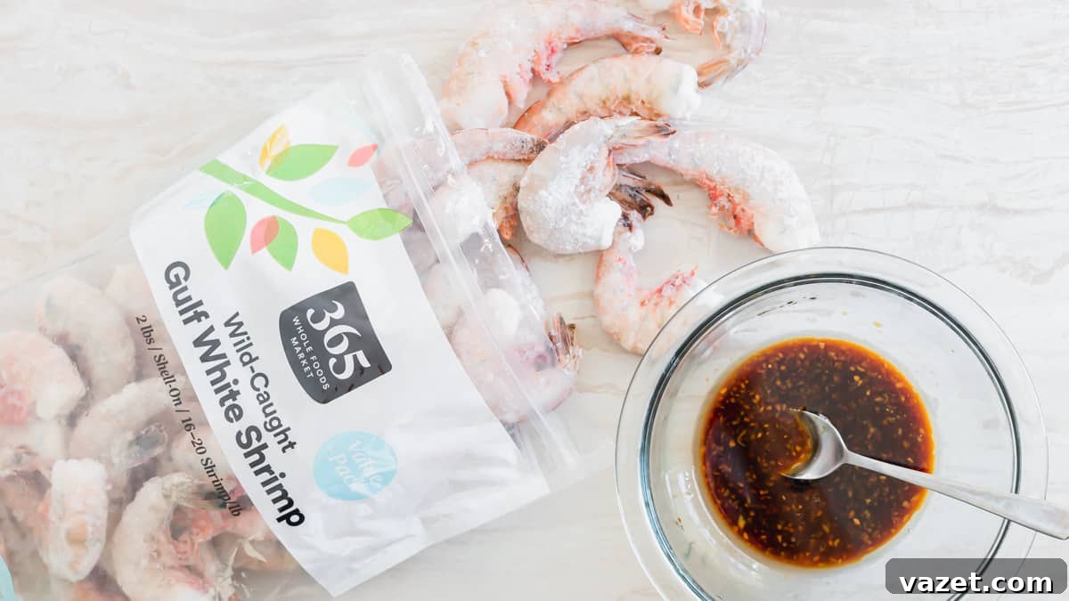 A close-up shot of several raw, peeled, and deveined shrimp laid out, showing their uniform size.