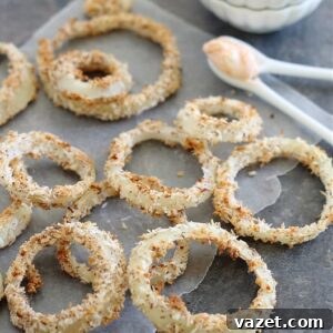 Finished coconut baked onion rings in a small bowl, garnished with fresh herbs.