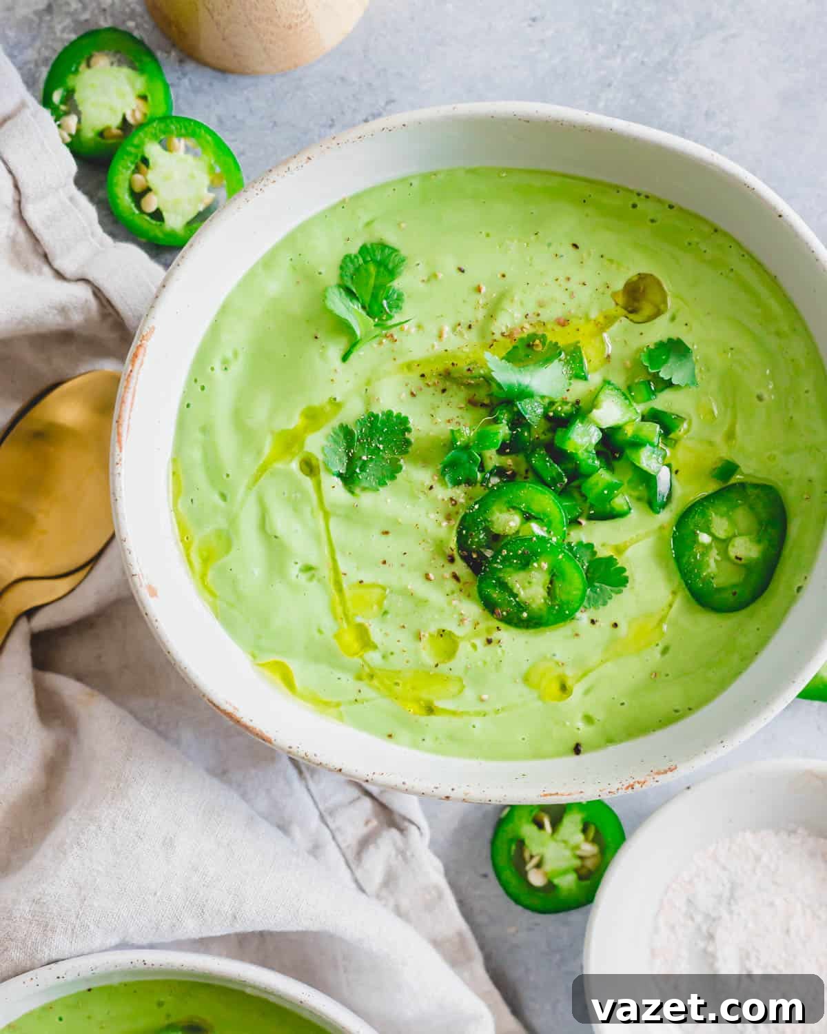 Chilled avocado soup in a bowl drizzled with olive oil and garnished with jalapeño peppers, cilantro, salt and pepper. Chilled avocado soup in a bowl drizzled with olive oil and garnished with jalapeño peppers, cilantro, salt and pepper.