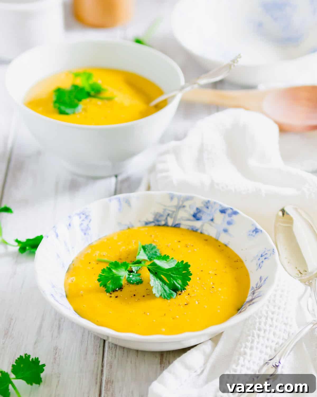 Velvety Pumpkin Potato Soup 2 Creamy pumpkin potato soup in a blue and white bowl, garnished with fresh parsley.