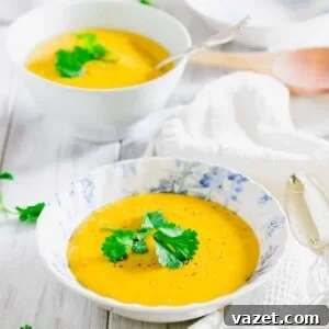 Pumpkin potato soup in a blue and white bowl garnished with fresh parsley.