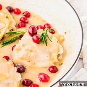 Chicken breasts in creamy white sauce, garnished with fresh cranberries and rosemary