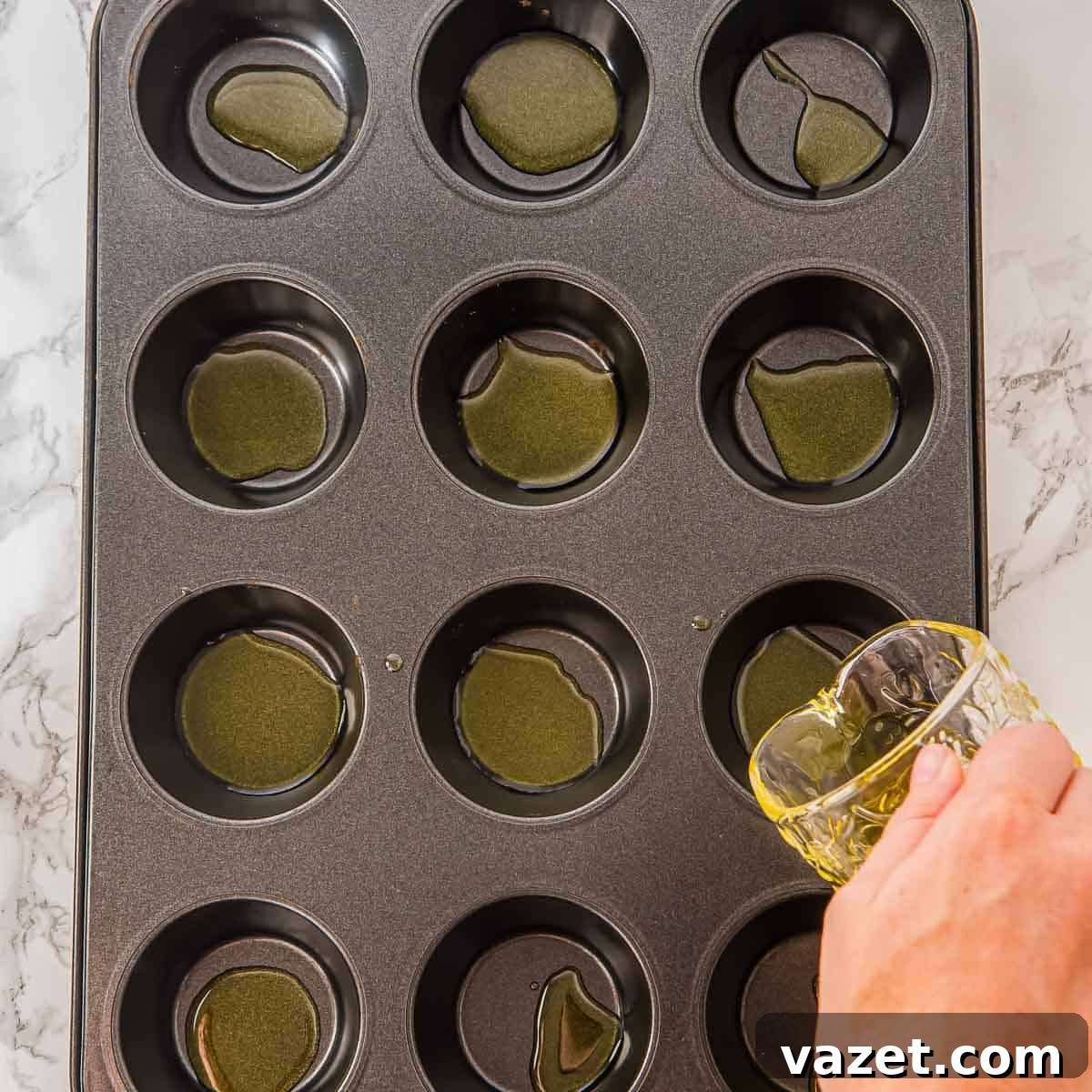 Greasing a muffin tin with olive oil.