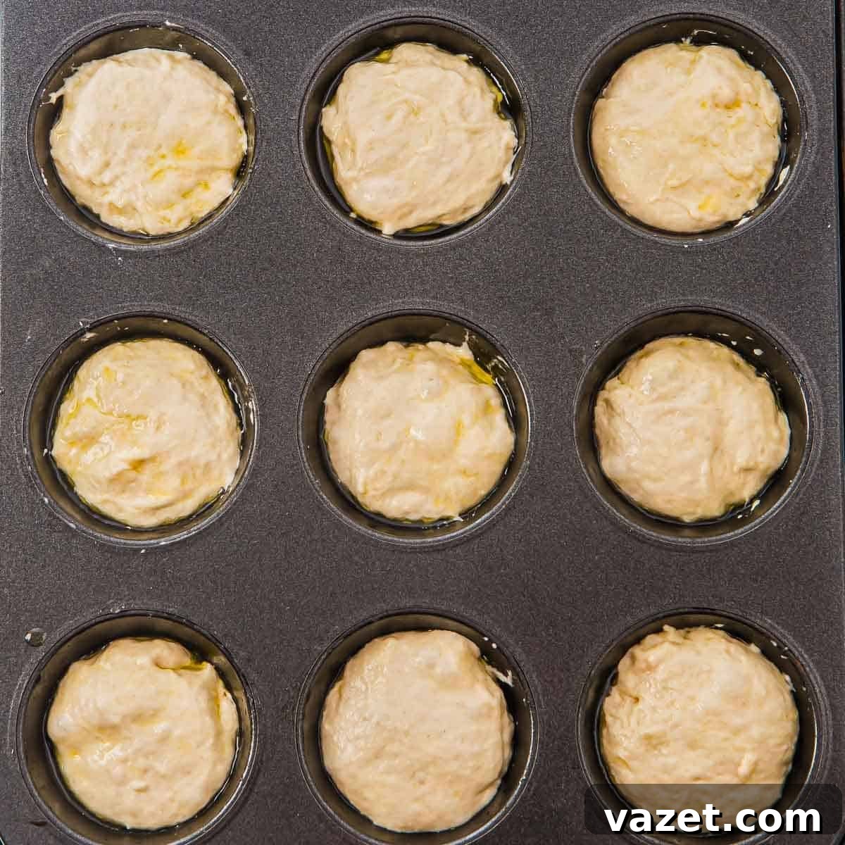 Muffin tin filled with focaccia dough, ready to rise.