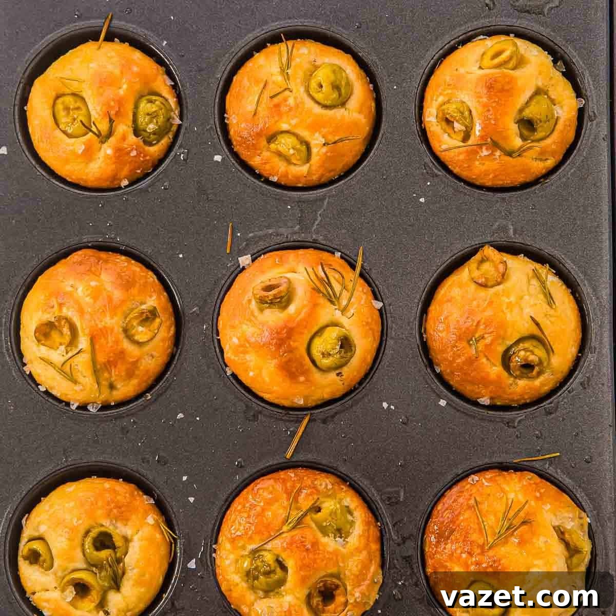 Baked focaccia muffins topped with olives, rosemary, and sea salt.