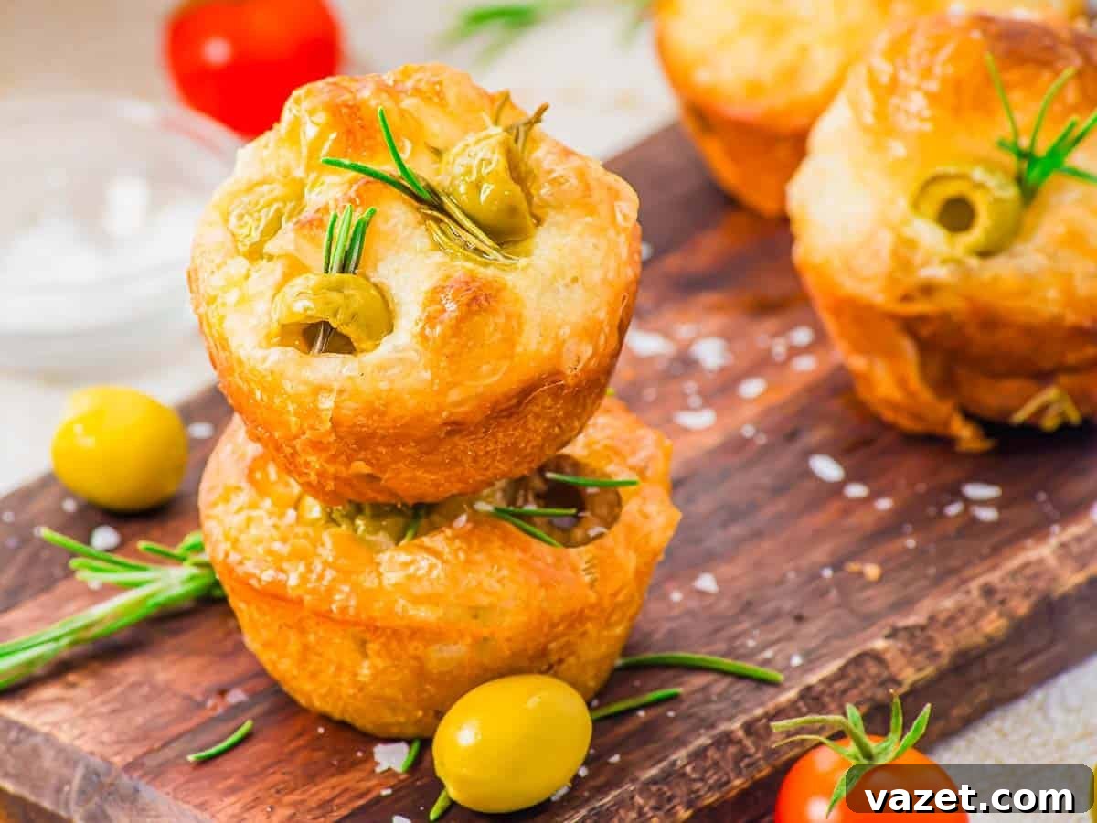 Savory focaccia muffins with olives and rosemary on a wooden board.
