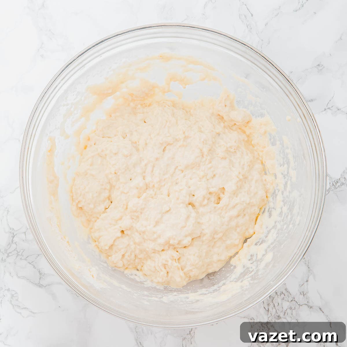 Sticky focaccia dough in a glass bowl.