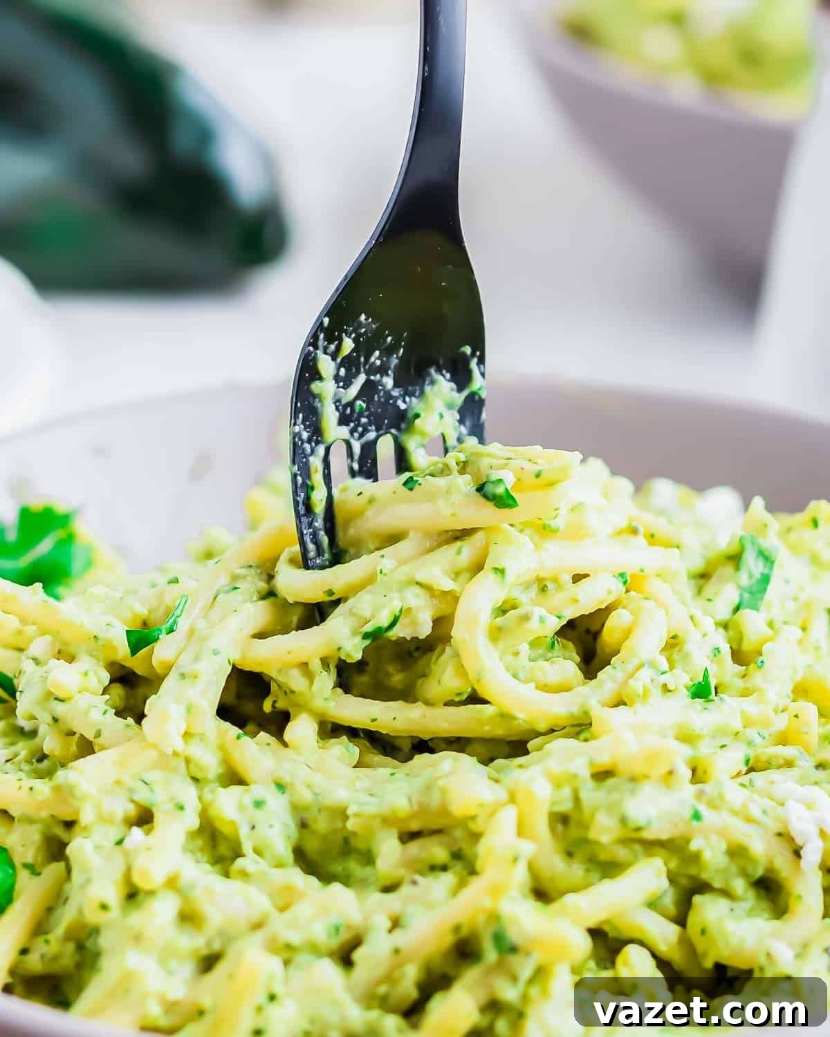 A close-up shot of creamy, vibrant green Espagueti Verde being twirled on a fork, highlighting the fresh herbs and delicious sauce.