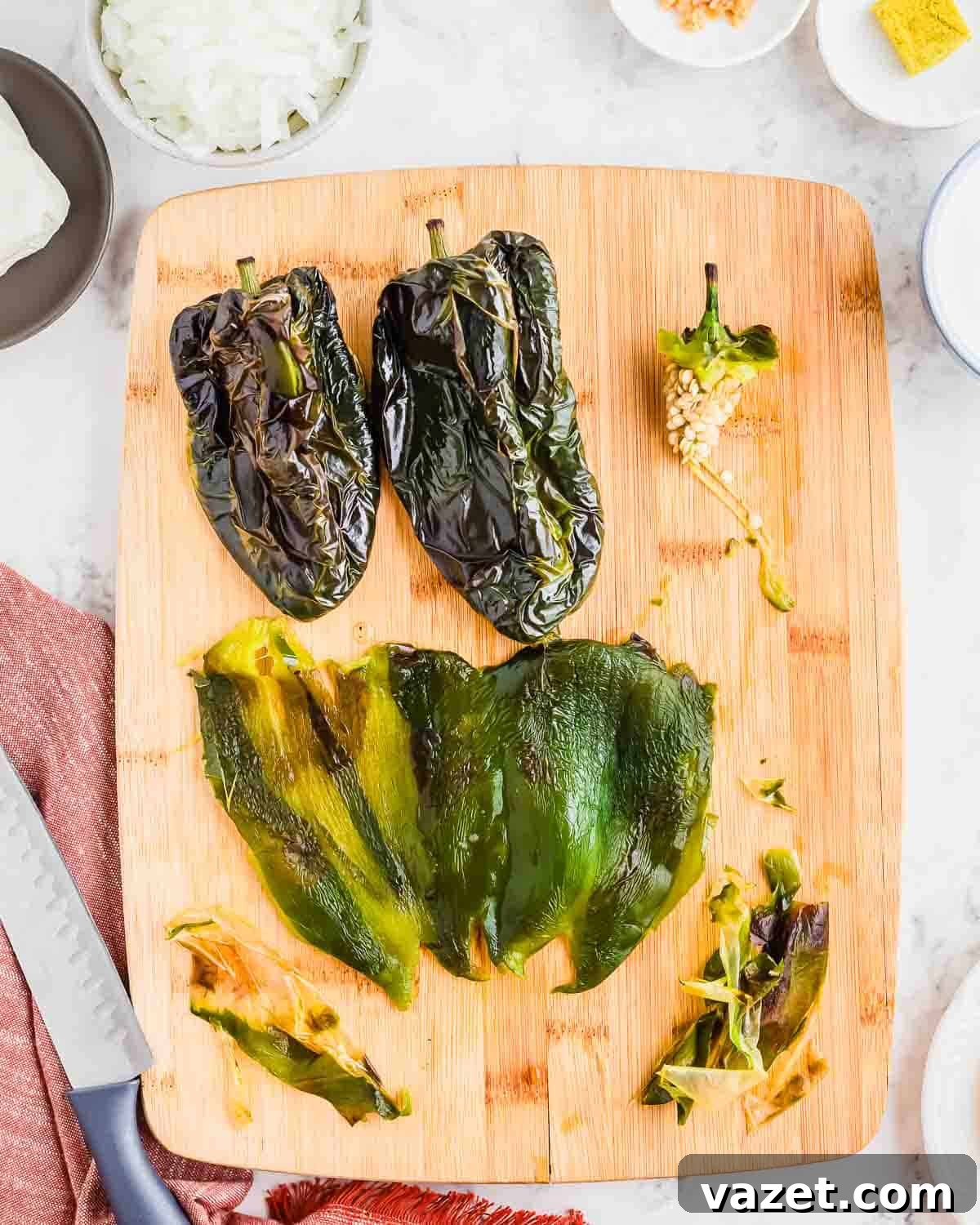 Roasted poblano peppers on a cutting board, some whole, some peeled and seeded, ready to be blended into a creamy sauce.