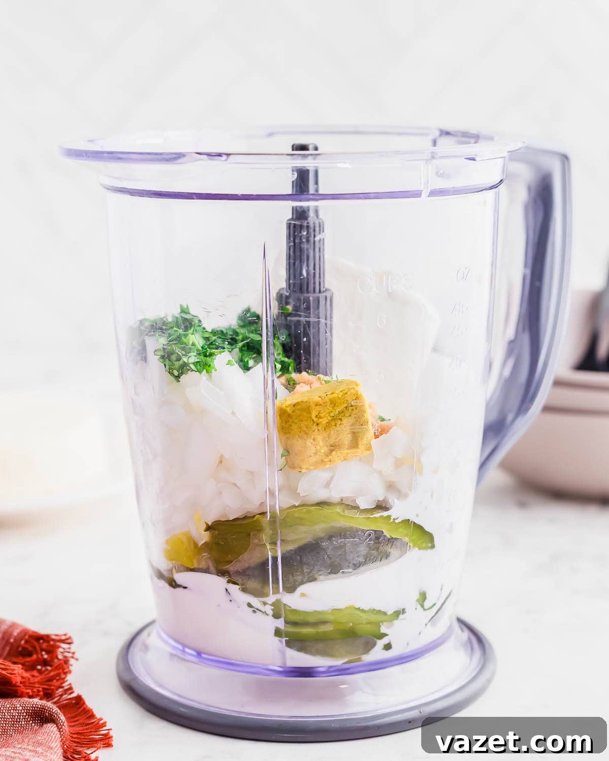 A blender filled with all the ingredients for the Espagueti Verde sauce, including roasted poblano peppers, onion, herbs, bouillon cube, and creamy ingredients.