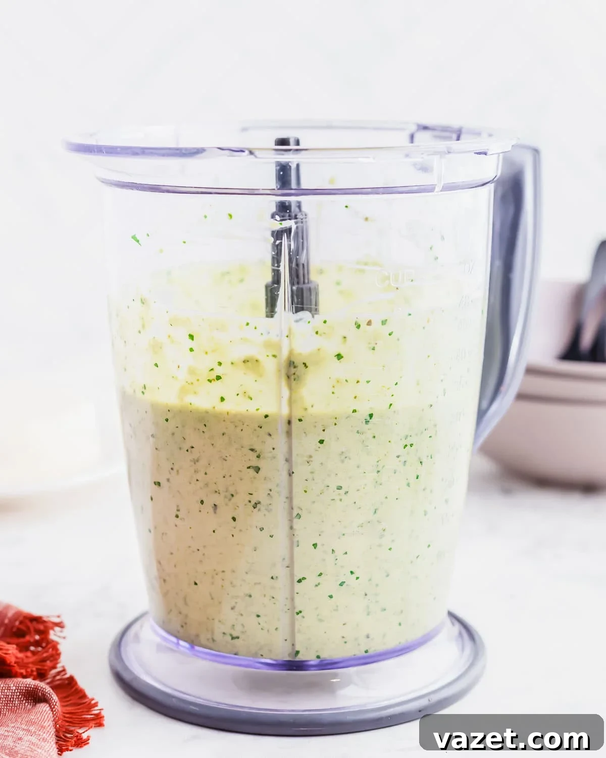 A blender pitcher filled with the smooth, creamy, green Espagueti Verde sauce, speckled with fresh herbs.