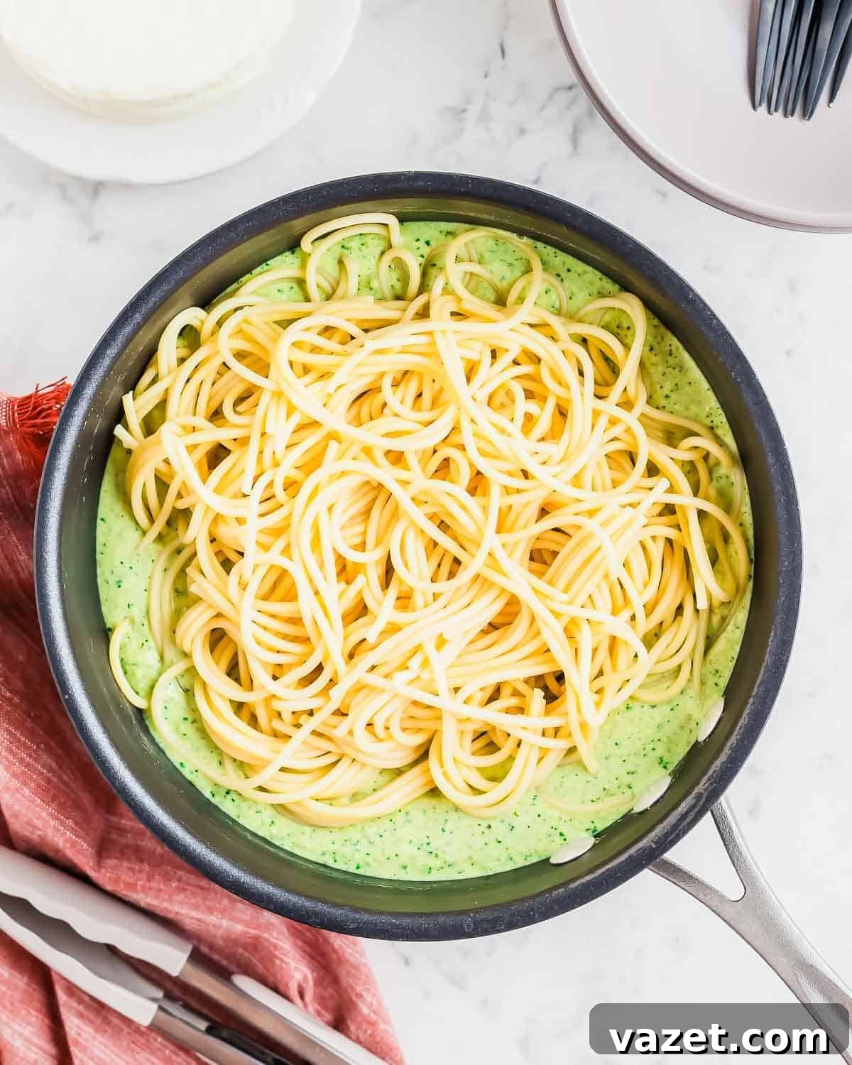 Cooked spaghetti tossed in the creamy green poblano sauce in a skillet, ready to be served.
