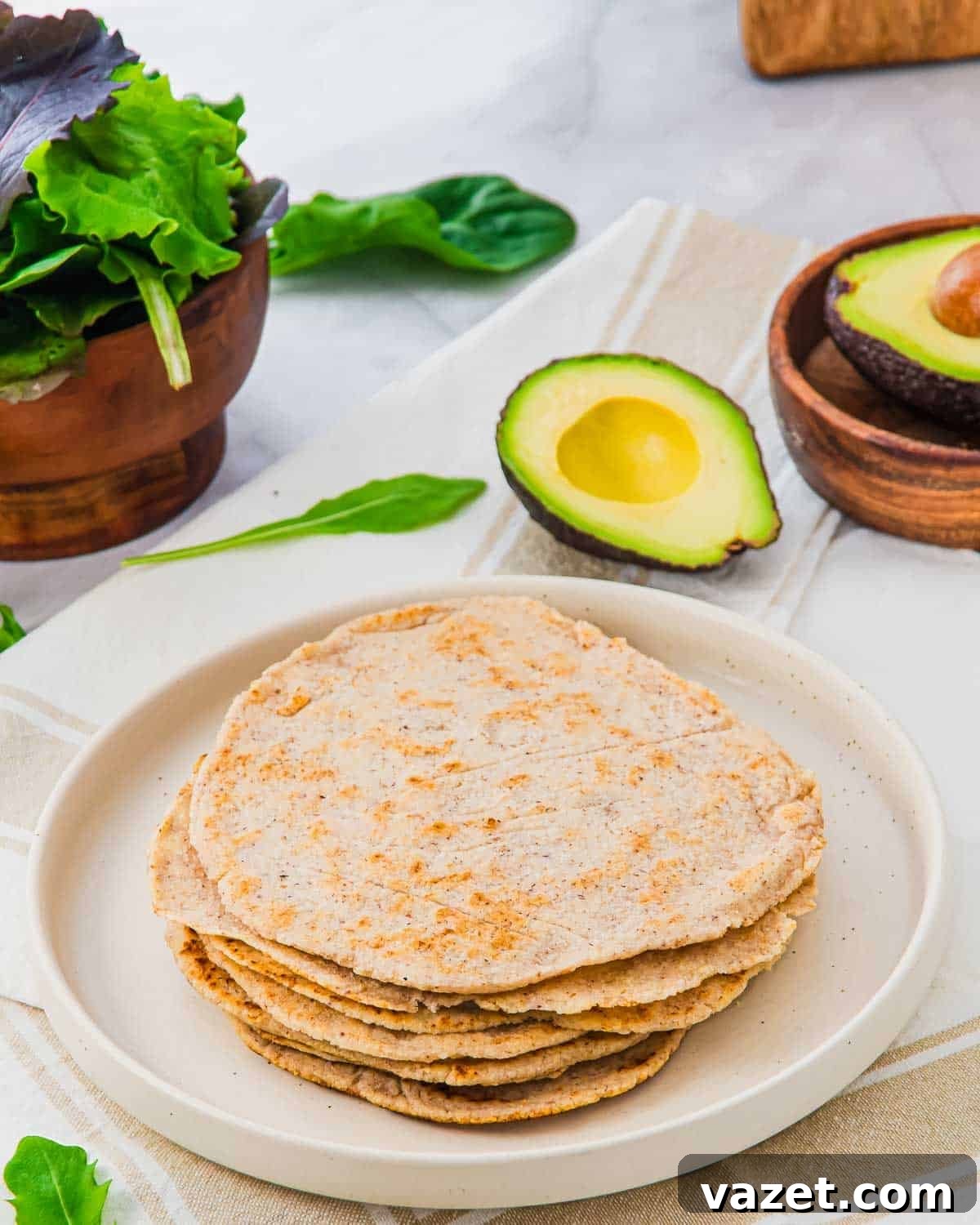 A stack of almond flour tortillas served with avocado and greens.