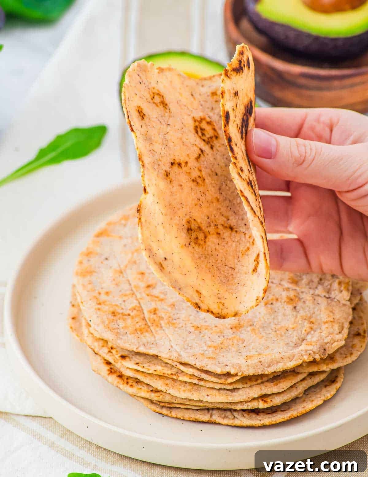 A hand lifting a freshly made almond flour tortilla.