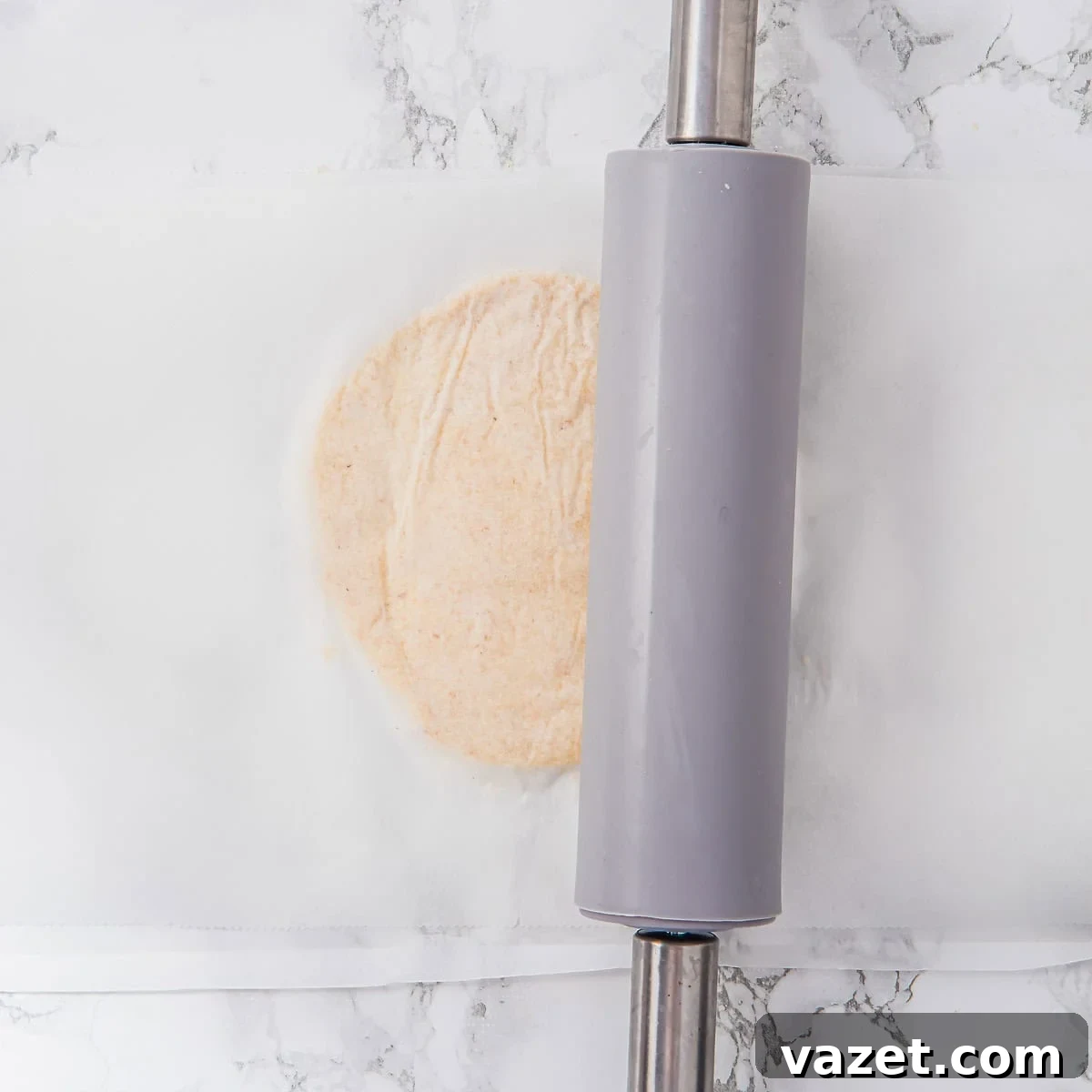 Rolling out the dough between parchment paper.