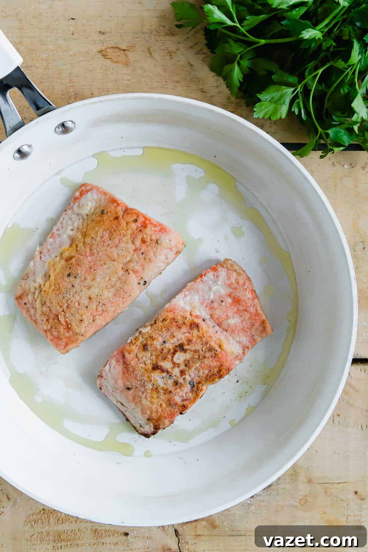Lemon Butter Salmon Piccata with Capers and Parsley 5 Two salmon filets in a skillet with oil.