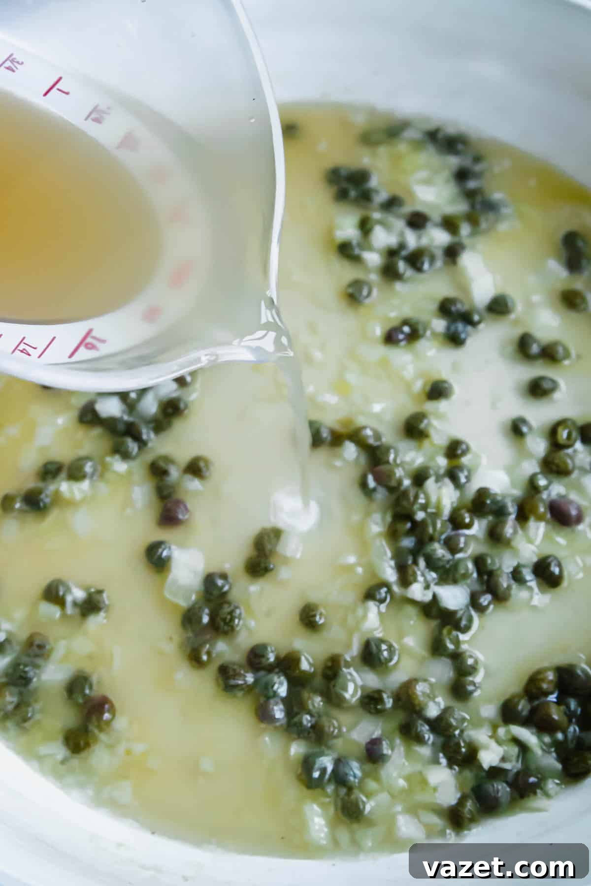 Lemon Butter Salmon Piccata with Capers and Parsley 6 Pouring broth into a skillet with shallots and capers.