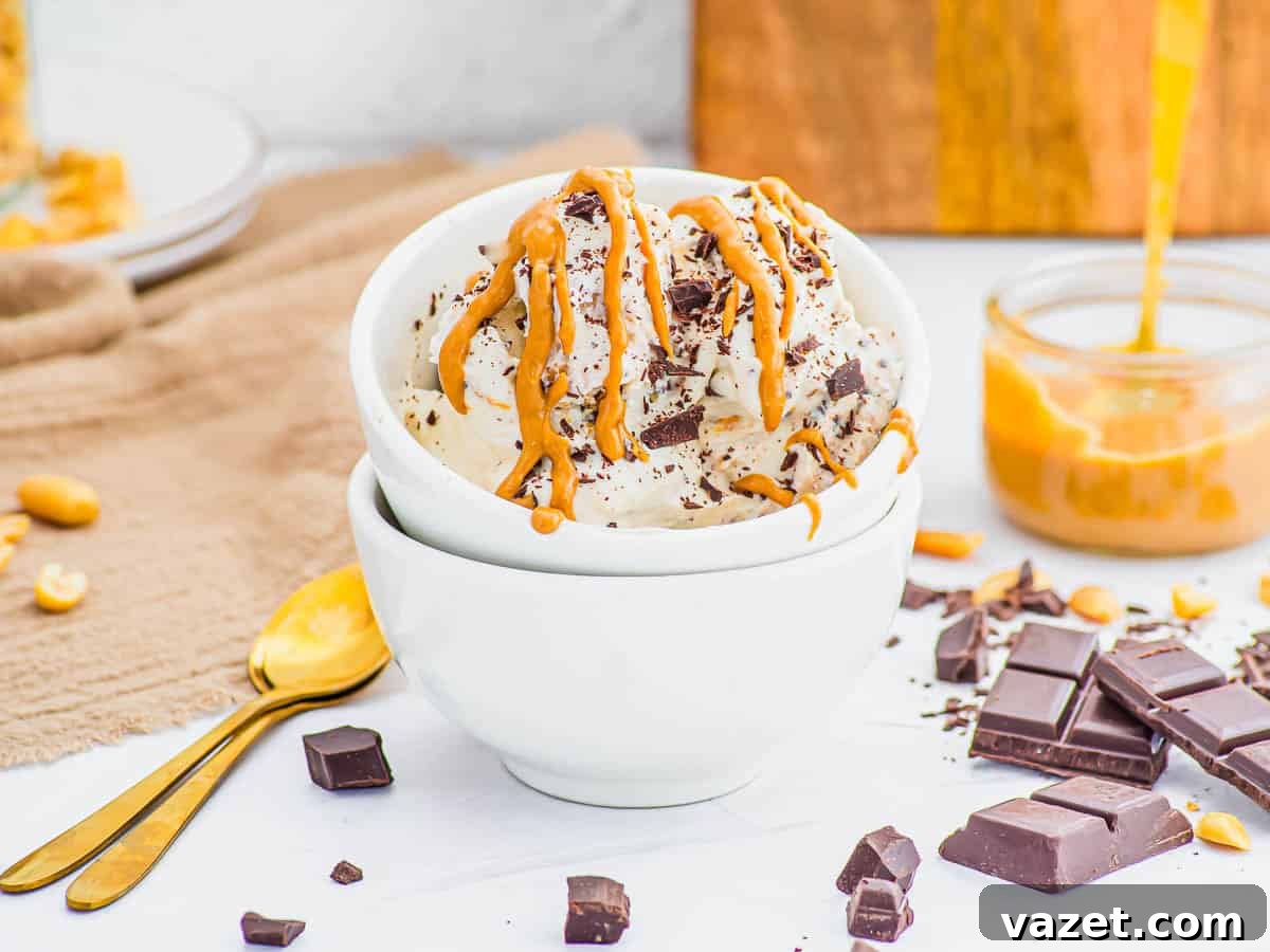 A bowl of vanilla cottage cheese ice cream topped with chocolate chunks and drizzled with peanut butter, surrounded by chocolate pieces, peanuts, and a jar of peanut butter.